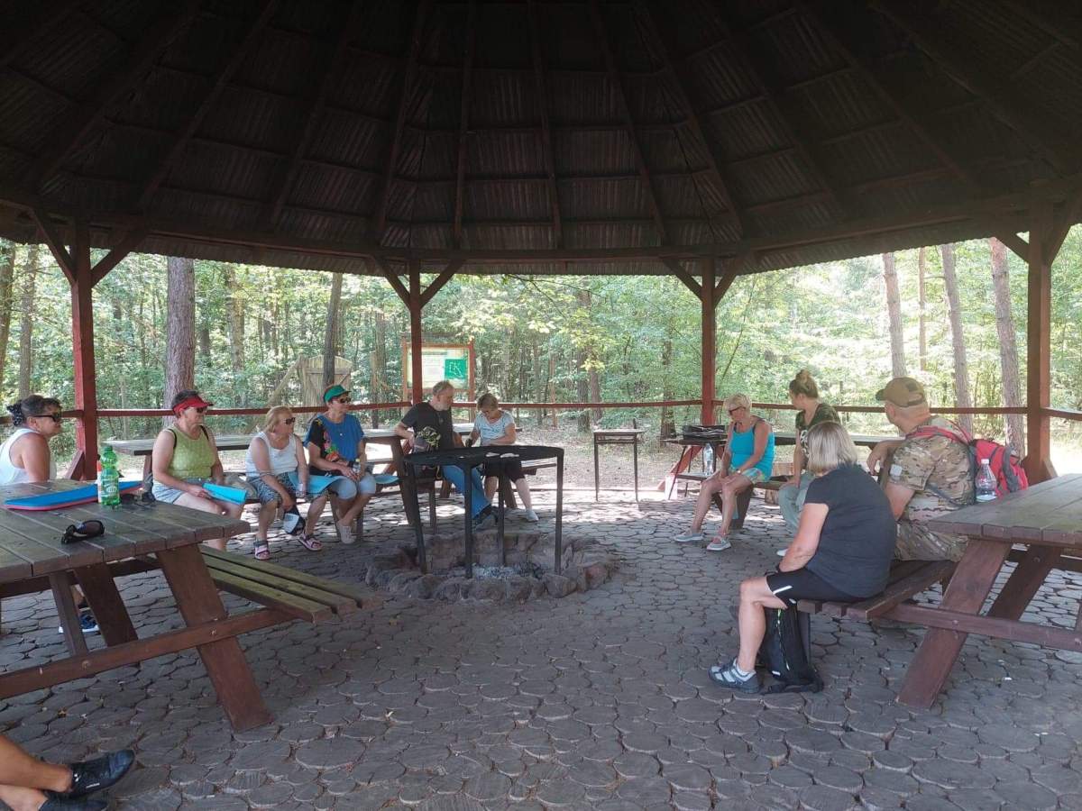 Grupa uczestników zajęć podczas pogadanki przy leśniczówce
